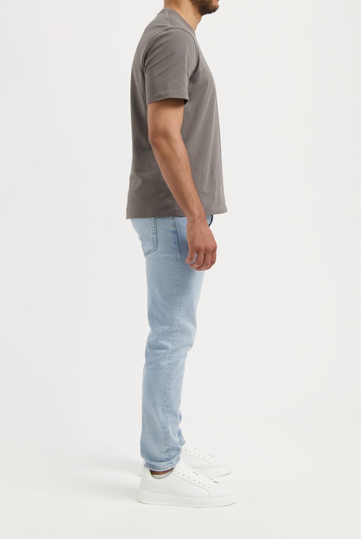 Sustainable MUD Jeans in beige, crafted from organic cotton, styled with a gray t-shirt and white sneakers.