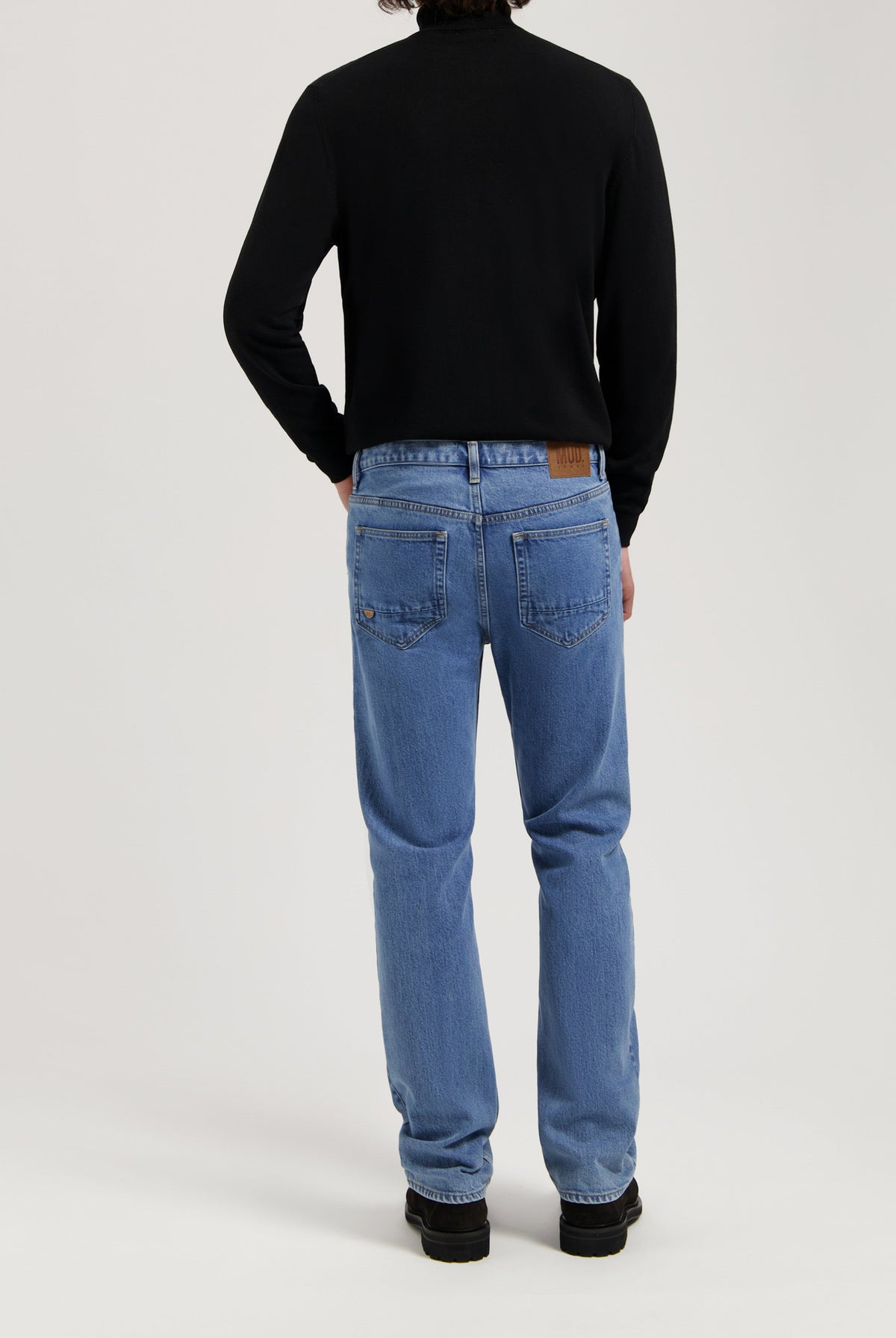Sustainable MUD Jeans in classic blue denim, crafted from ethical materials, paired with a sleek black sweater.