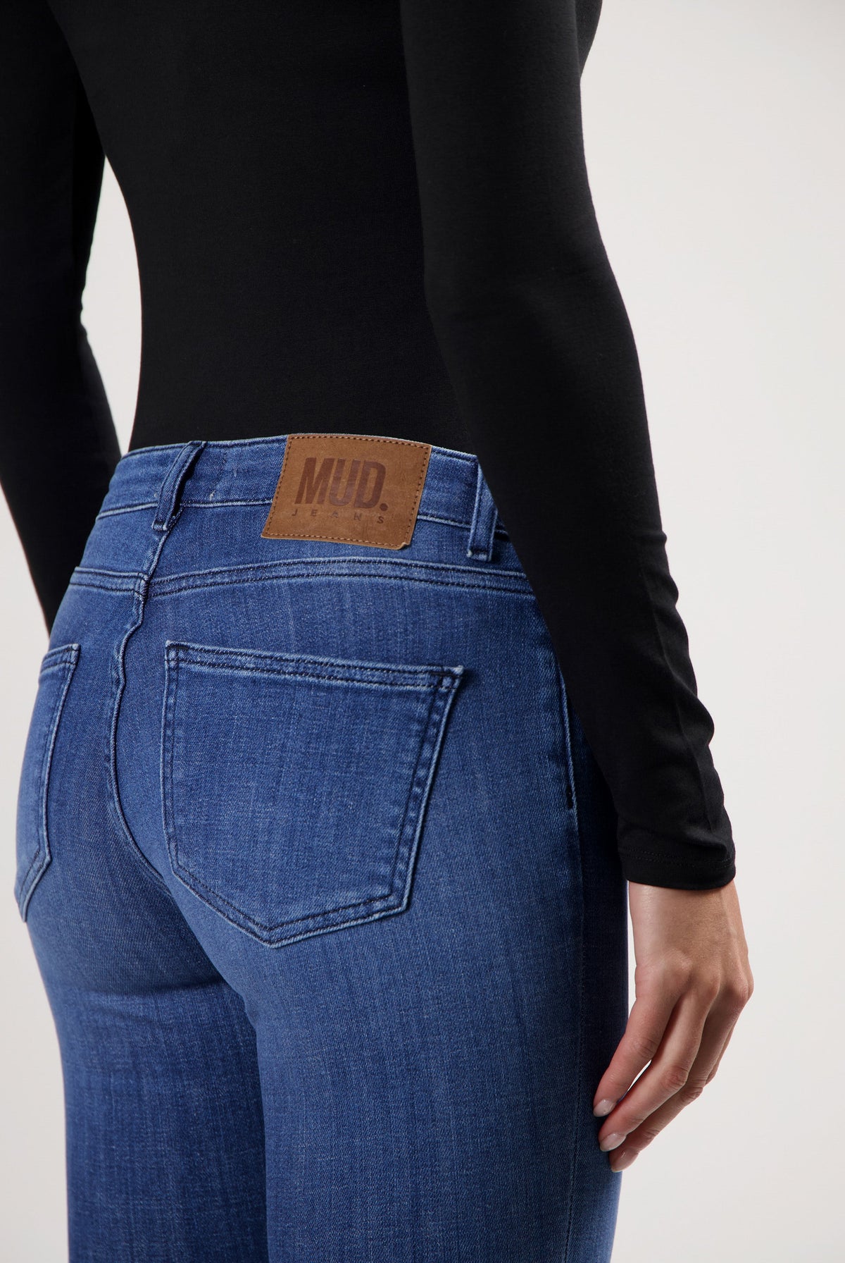 Slim-fit blue MUD Jeans crafted from sustainable cotton, shown with a black long-sleeve top, emphasizing eco-friendly fashion.