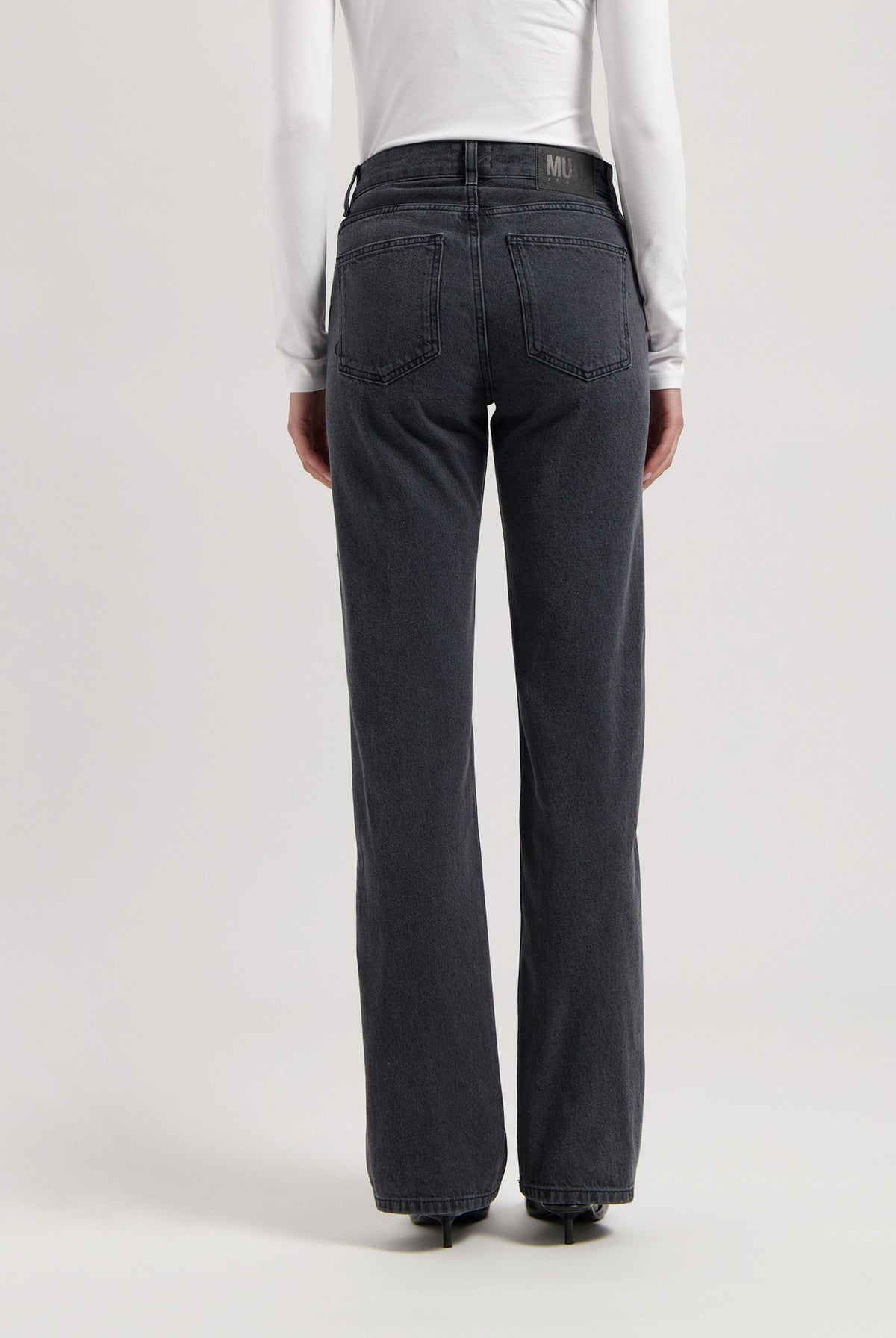 High-waisted, dark gray straight-leg jeans from MUD Jeans, featuring a subtle back pocket design, paired with a white long-sleeve top.