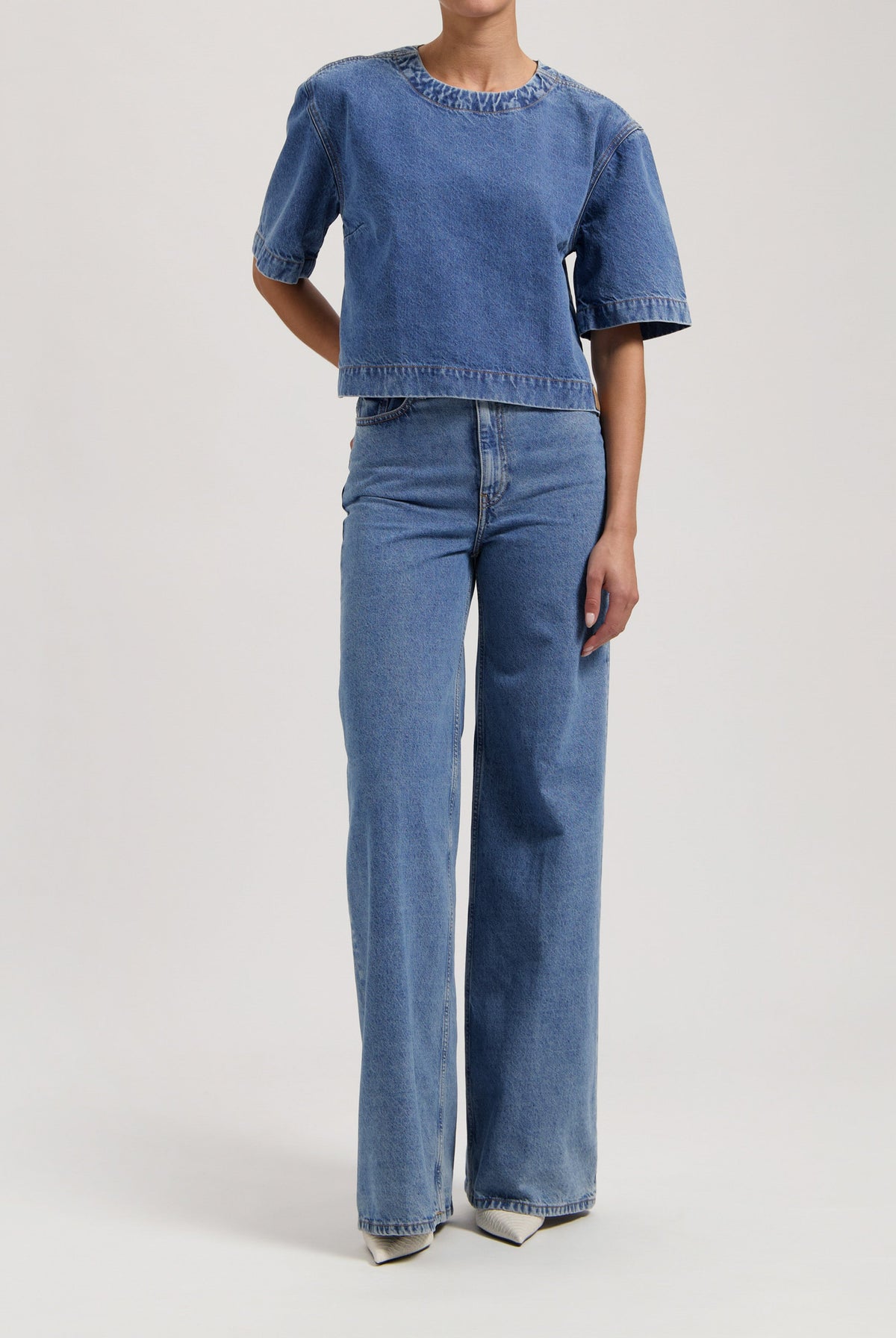 Model wearing blue denim two-piece outfit with short-sleeve top and wide-leg jeans, showcasing casual fashion style.