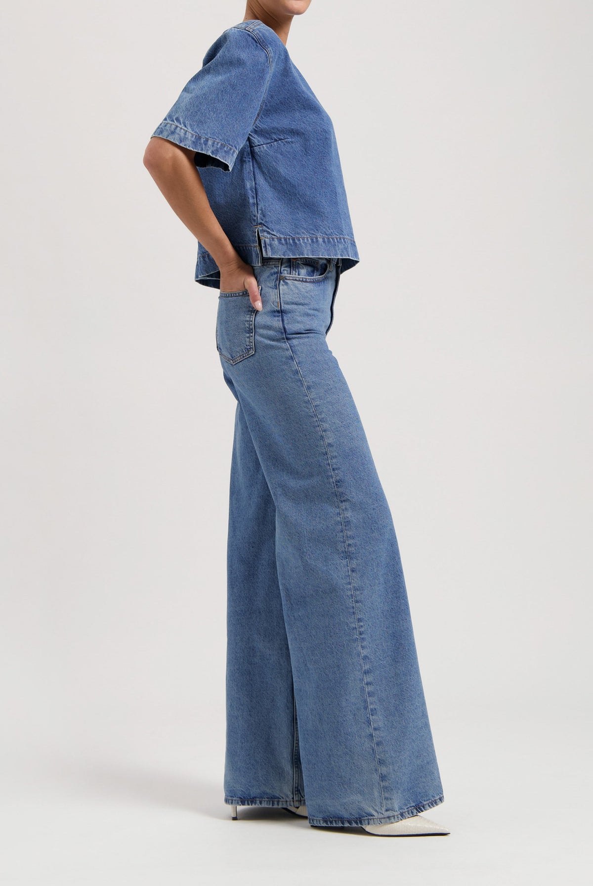 Wide-leg denim jeans paired with a loose short-sleeve denim top, creating a relaxed casual outfit on a neutral background.