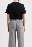 Sustainable MUD Jeans in dark brown, crafted from organic cotton, worn with a white t-shirt and white sneakers.