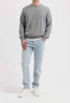 Sustainable MUD Jeans in gray denim, featuring an ethical, classic fit, paired with a black sweater and sneakers.