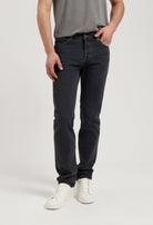 Sustainable MUD Jeans in dark denim, ethically made with organic cotton, paired with black loafers and white ribbed sweater.