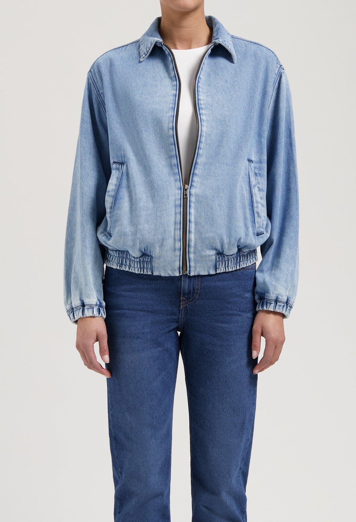 Light blue denim jacket with elastic cuffs paired with classic medium-wash jeans, showcasing casual, relaxed fit fashion.