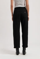 Black high-waisted jeans made of cotton, shown from the back, paired with black boots and a light gray sleeveless top.