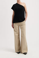 One-shoulder black top paired with wide-leg beige trousers, showcasing casual yet elegant modern fashion style.