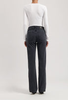 Person wearing dark gray straight-leg jeans with a high waist, paired with a fitted long-sleeve white top, viewed from the back.