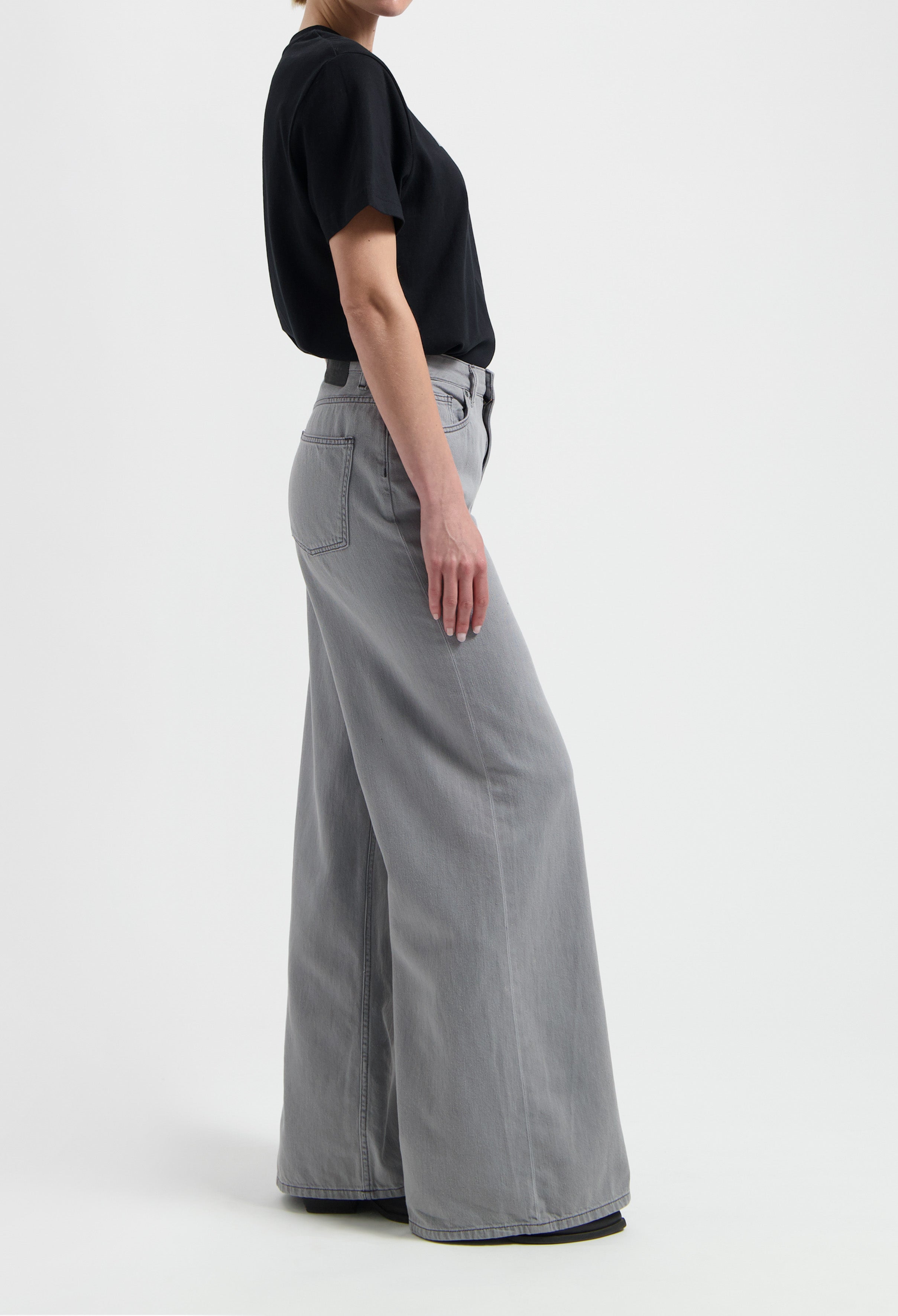 Wide-leg gray denim jeans paired with a simple black short-sleeve T-shirt, showcasing casual style for everyday wear.